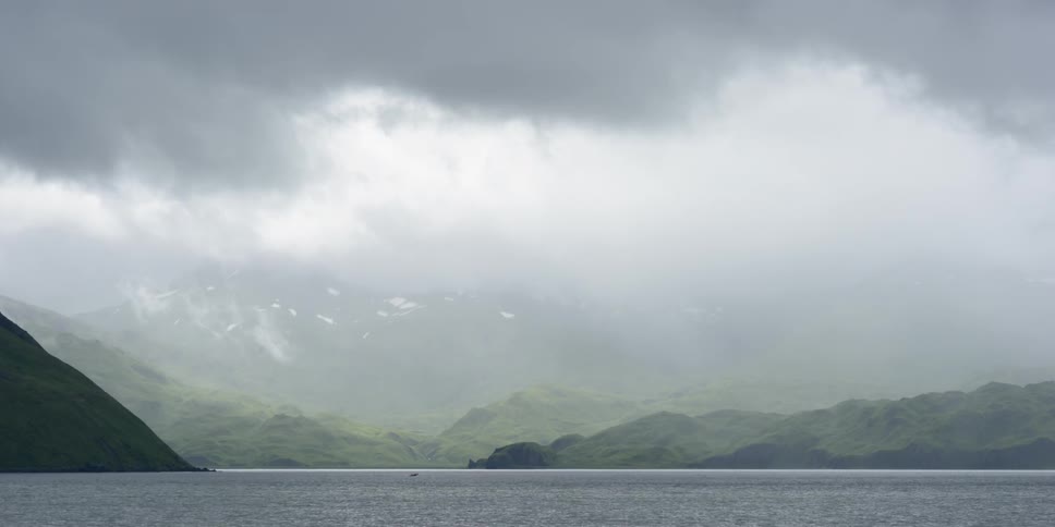 A large lake with rolling green hills in the distance