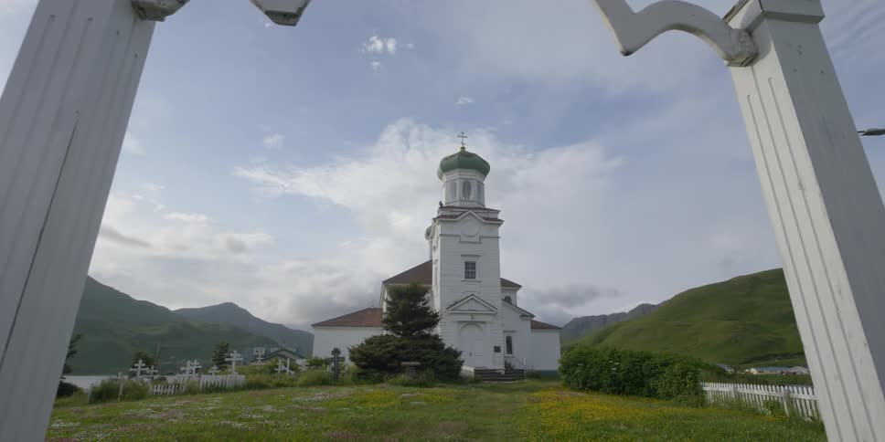 Clouds hover in the sky above a church and graveyard during the day
