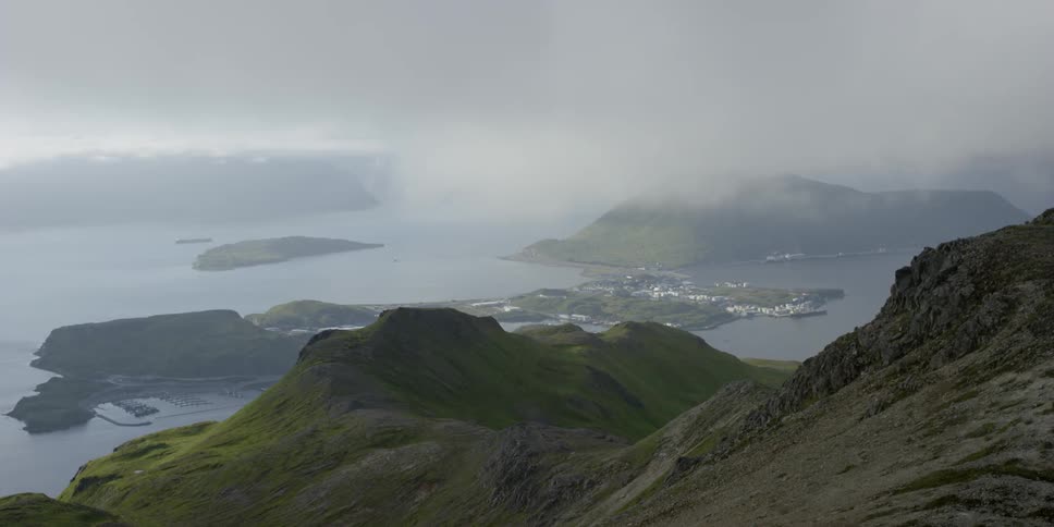 Clouds hover over ocean bay surrounded by mountains