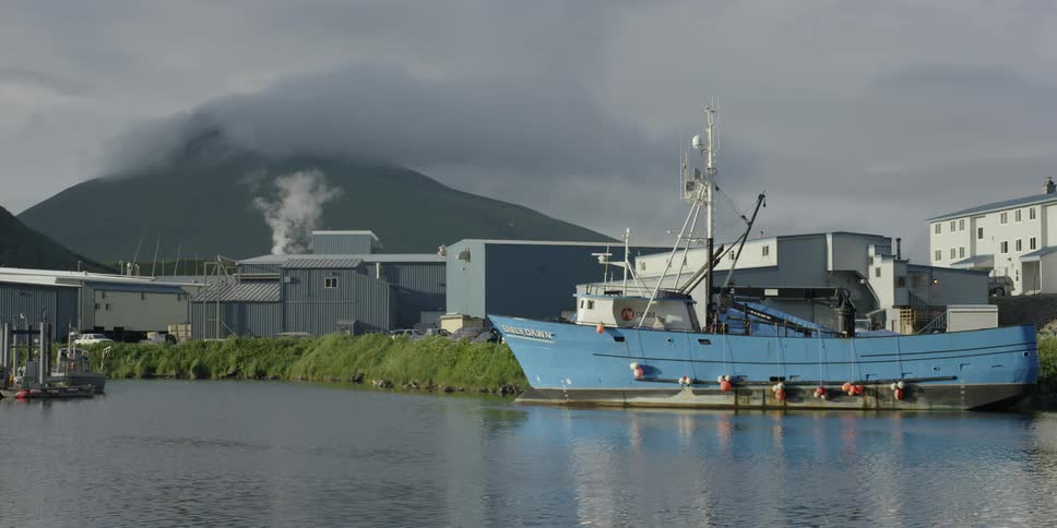 A ship is docked next to a factory