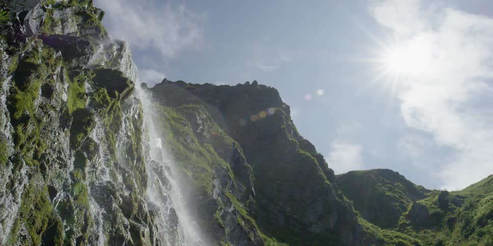 Water flows down a waterfall cliff on a sunny day
