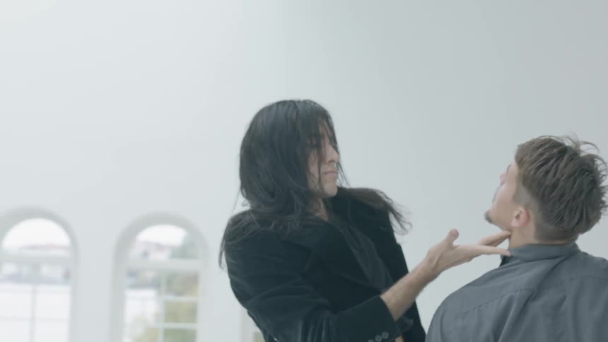 Two people are dancing in a large white room