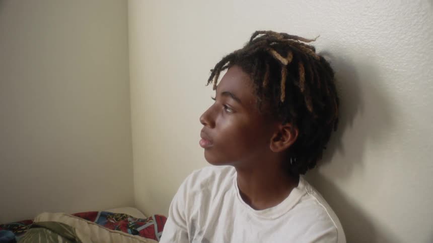 Boy sits on his bed thinking