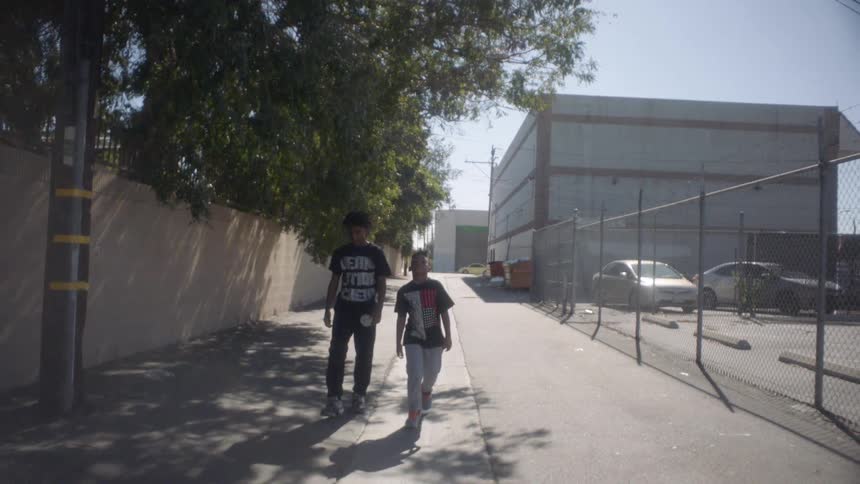 Two kids are walking down an alley