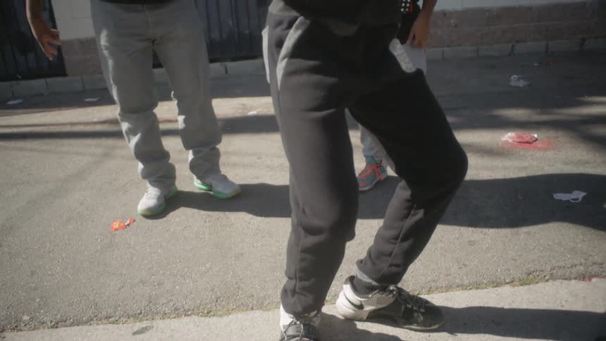 A boy is dancing as he stands outside with another child and an adult
