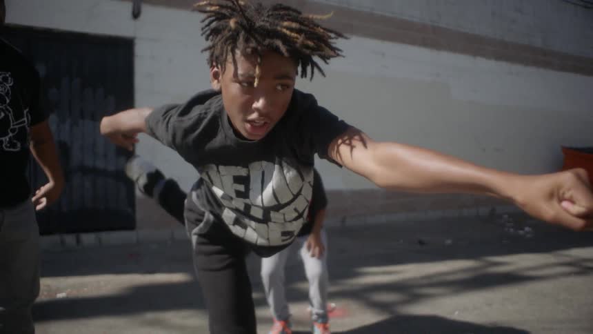A man and two kids dance in an alley