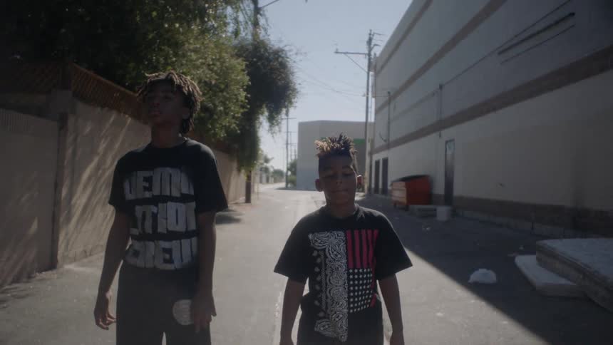 Two kids are walking behind a shopping center
