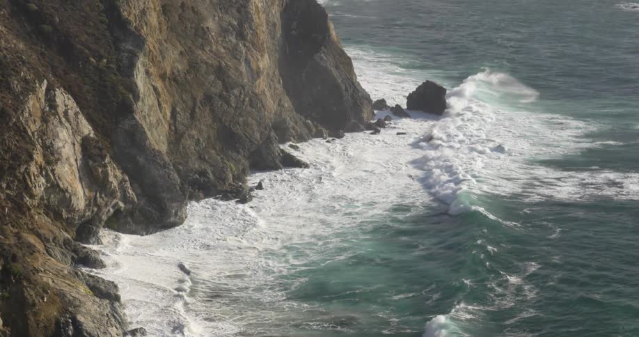 Ocean waves crash onto a cliff and beach
