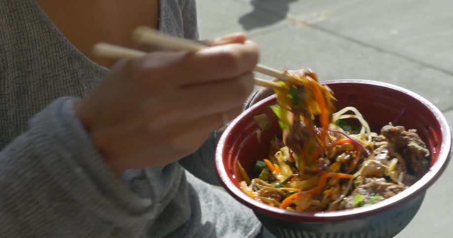 A woman eats a noodle bowl with chopsticks