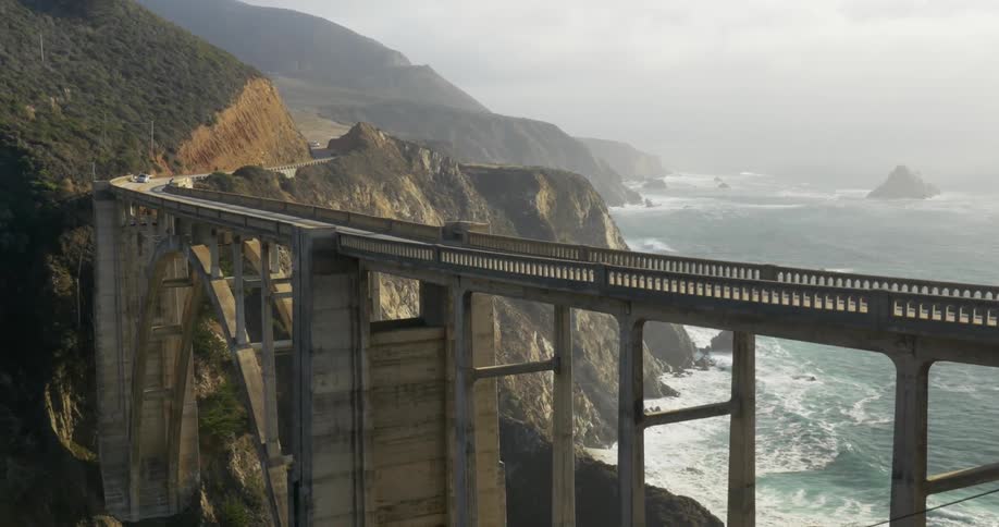 Cars crossing a tall bridge over the ocean