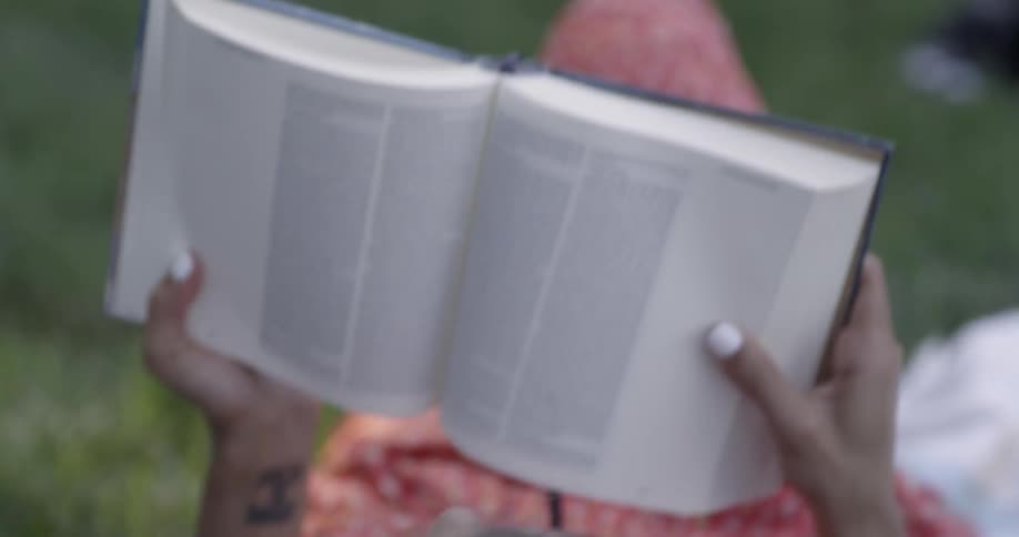 A man and woman cuddle on a blanket while reading