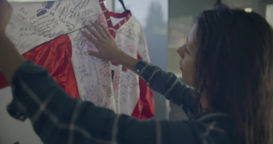 A woman is looking at a jersey with a bunch of signatures on it