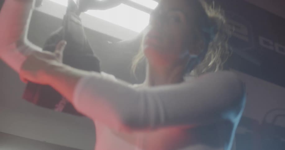 A woman fastens her arms in a piece of gym equipment