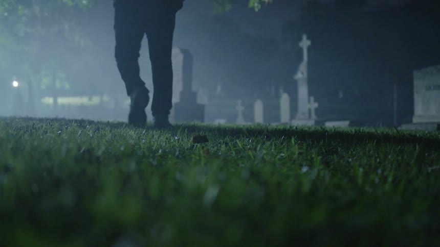 Man walks alone in a cemetery at night