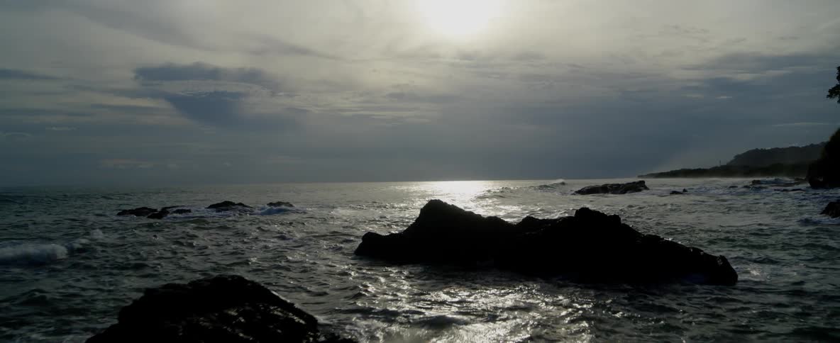 Choppy water is crashing onto large rocks sitting out of the water