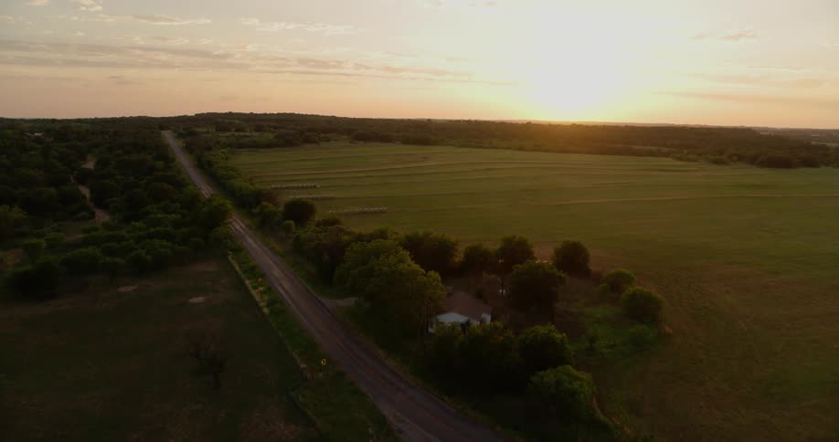 Sun sets over a large grassy field and farm