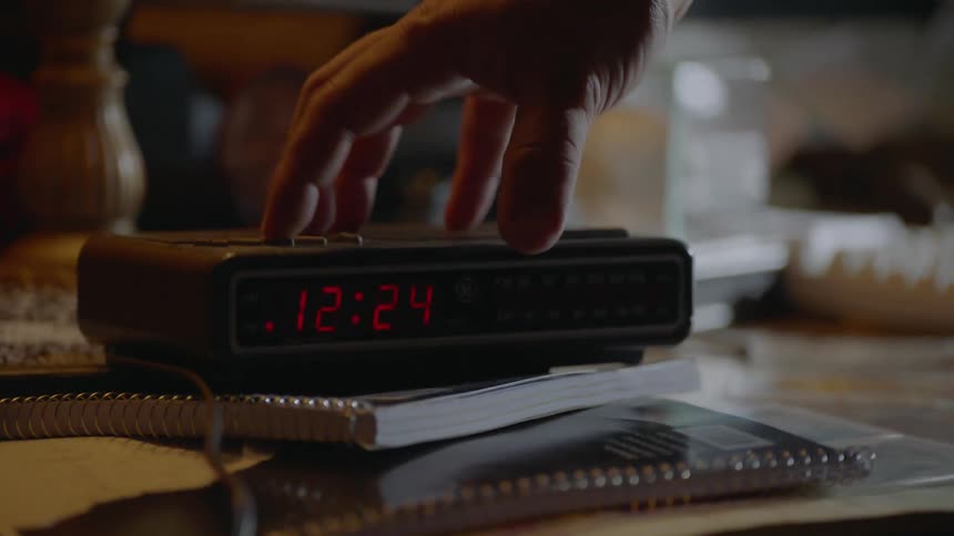 A man is setting the time on a digital clock in a room