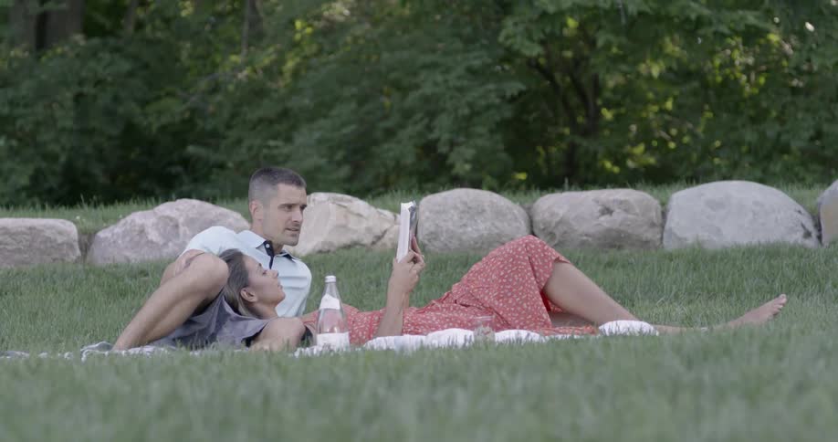 A man and women read a book together in a picnic