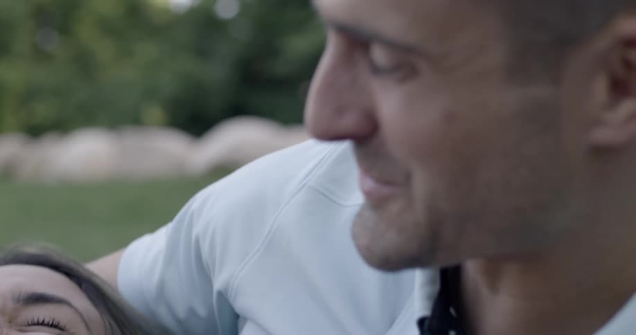 Woman lays in her lovers lap and smiles up at him