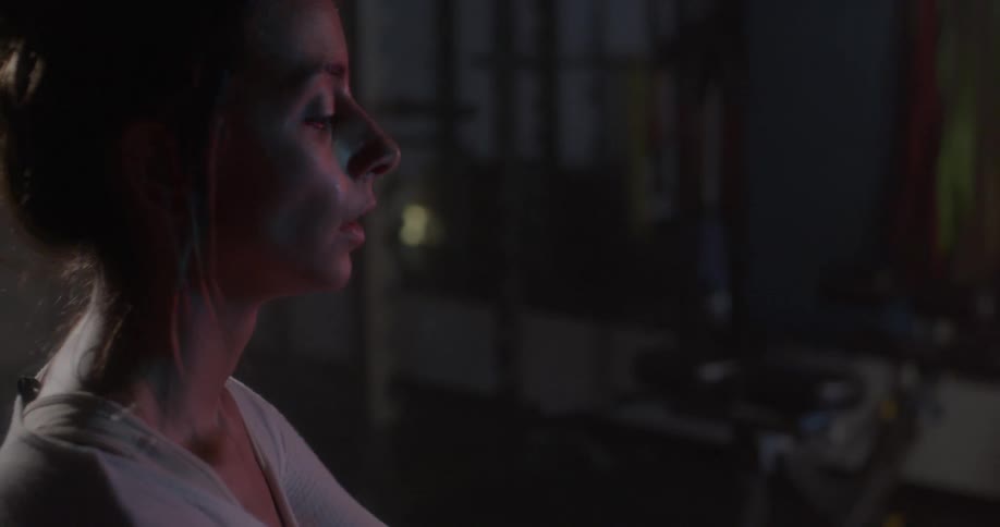 A woman is stretching in a dark gym