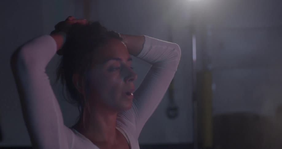 A woman has her hands on her head after working out in the gym