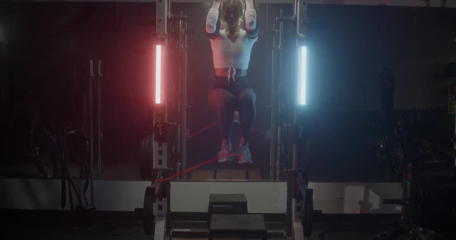 Woman exercising while hanging from some straps in a gym