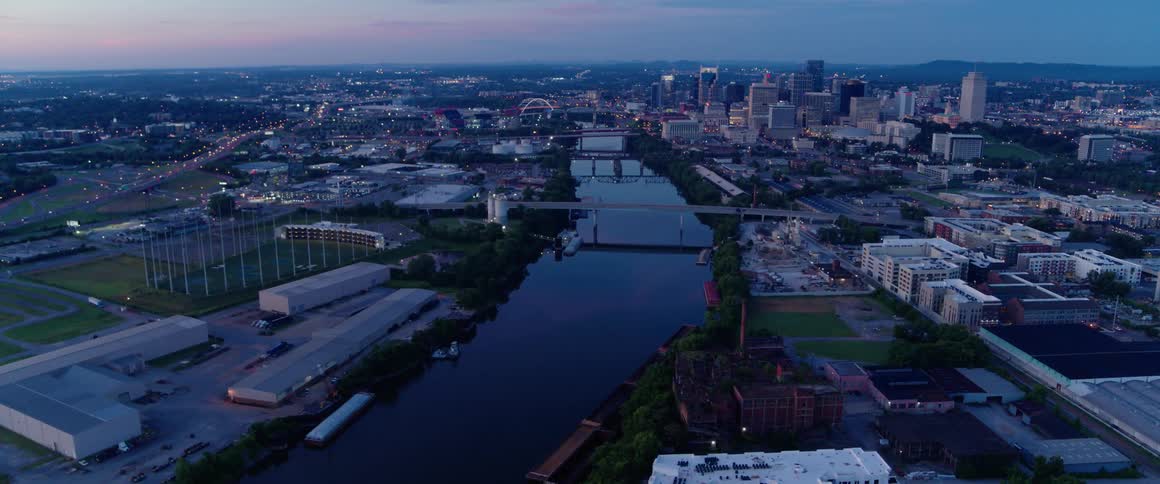 Aerial view of a river leading towards a large city at sunset