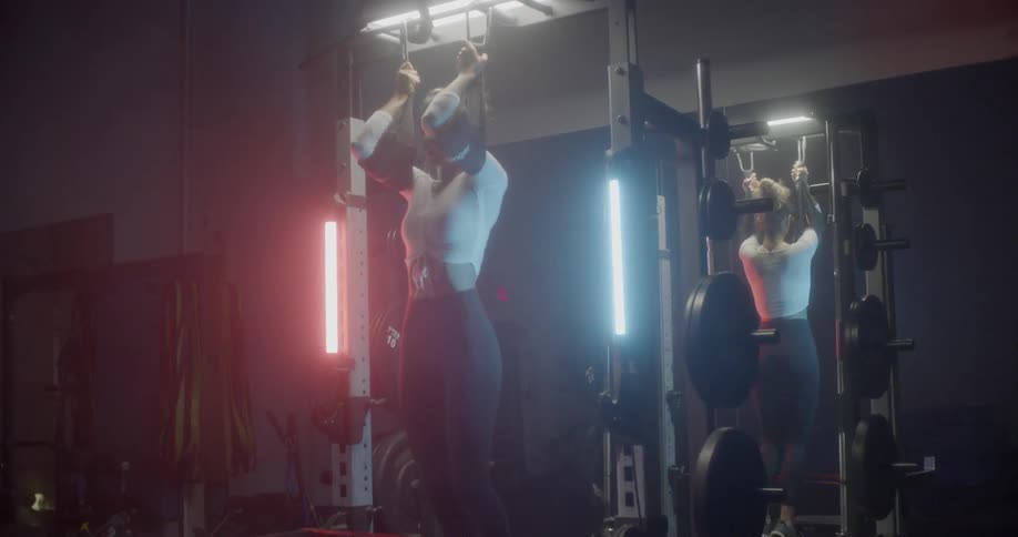 Woman doing pull ups on exercise machine in gym