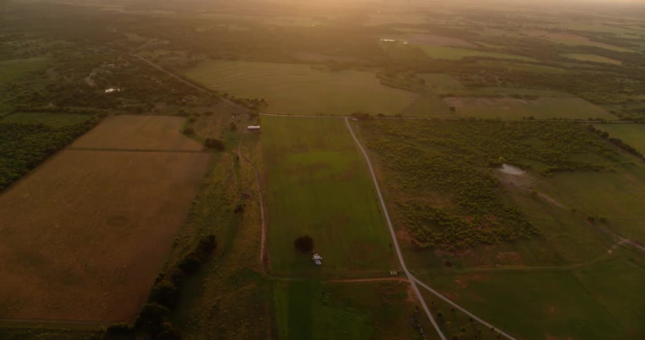 The farm below has the sun setting in the distance