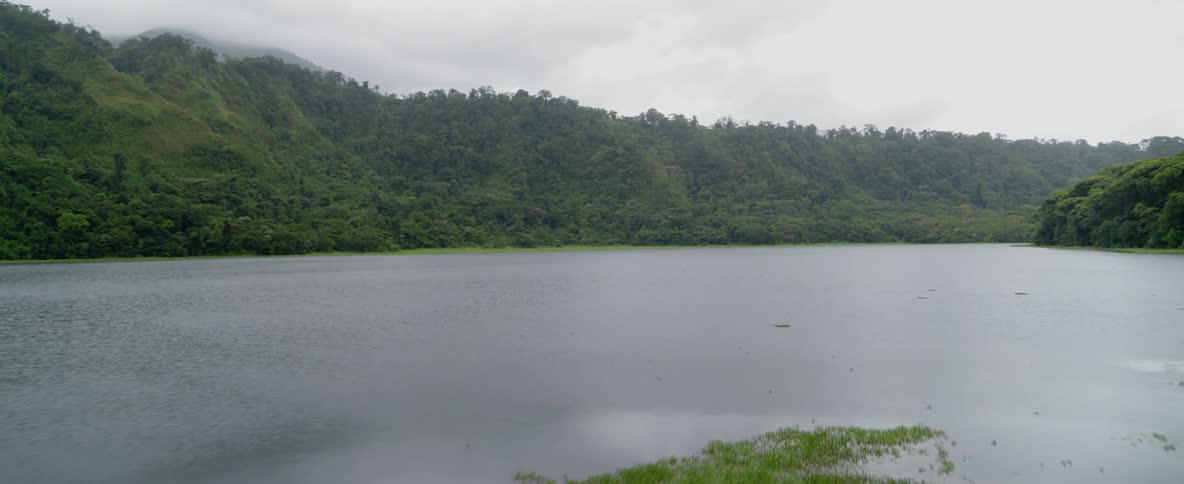 The lake is calm near the green hills