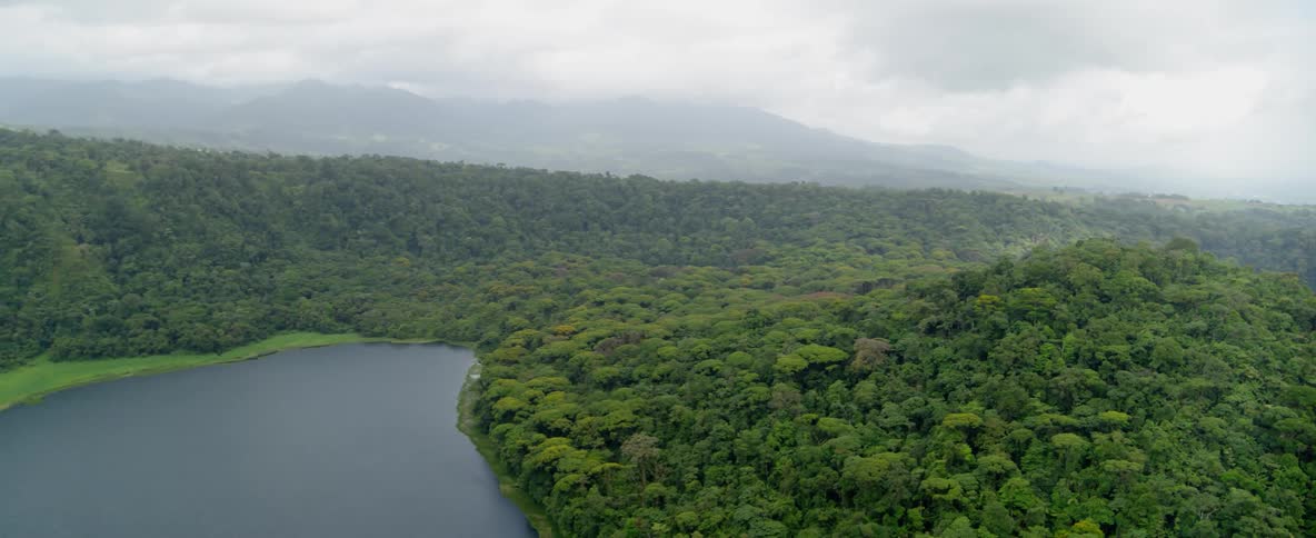 The water is calm near these hills filled with trees