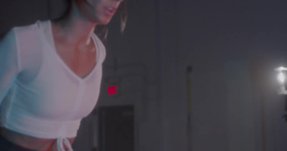A woman is leaping onto a platform in the gym and then stepping down