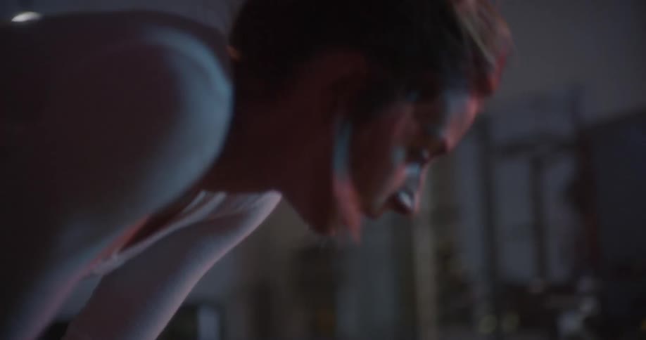 A woman bends over to catch her breath in a gym