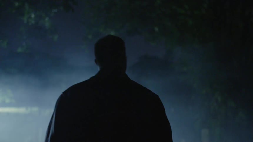 Man walks alone in a cemetery at night