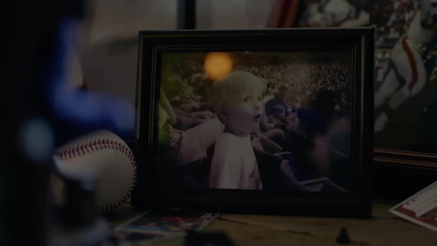 Person picks up a framed photograph sitting next to a baseball