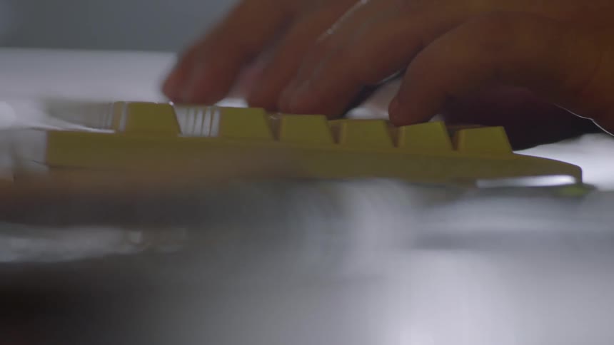 A man types on a yellow keyboard