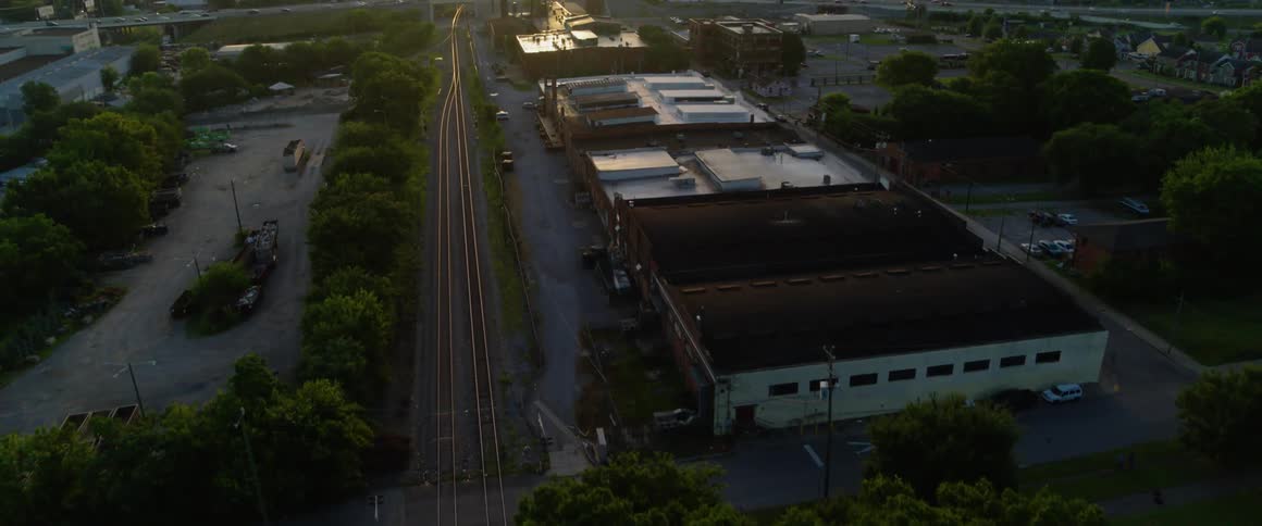 The train tracks lead to a city full of fast moving cars