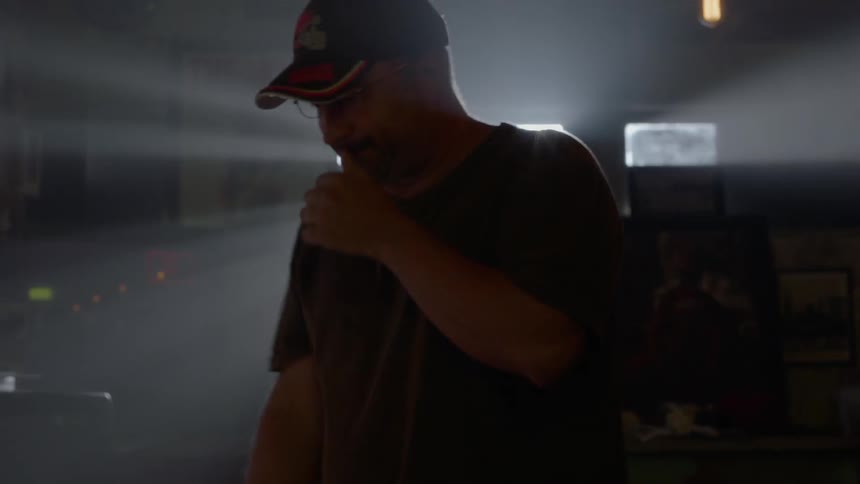 A man paces around in a dim room