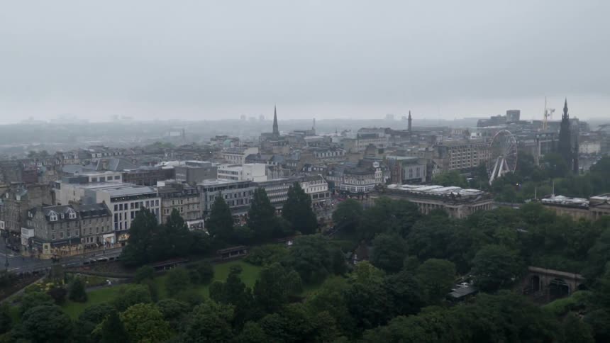 A ferris wheel set up in a city flashes on an overcast day