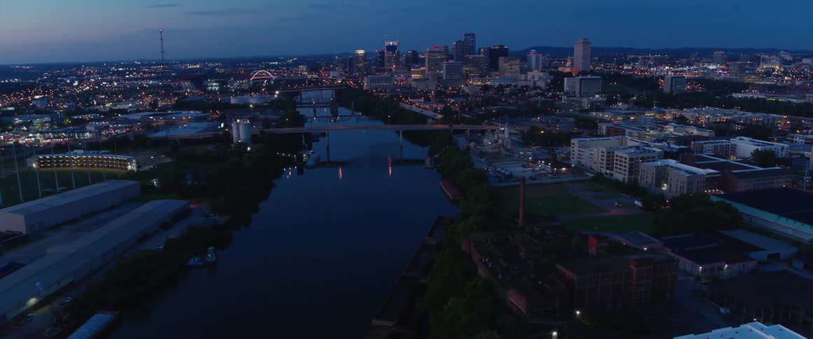 Lights reflect off the river water near a city at night