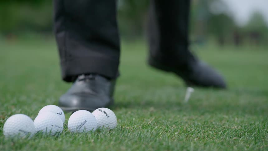 Man reaches down and selects a golf ball