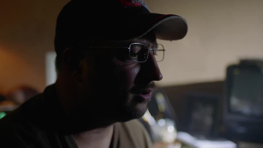 A man wearing glasses stares inside a room