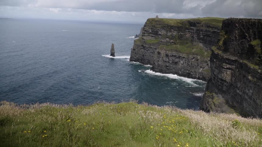 Ocean waves crash into the base of a rocky cliff