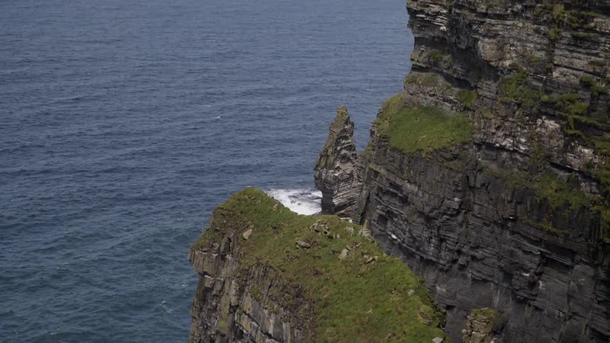 Birds are flying near rugged coastal cliffs on a sunny day