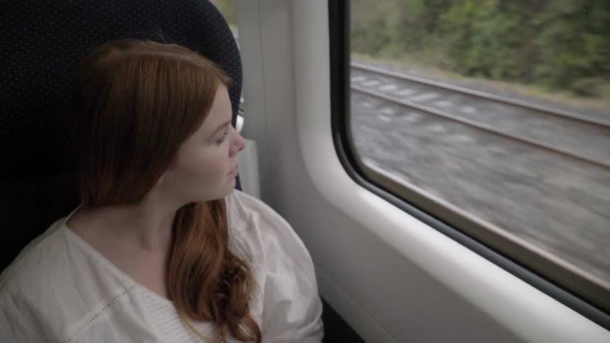 A girl looks out the window of a moving train