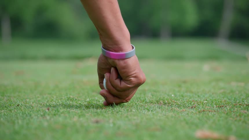 Golfer puts a golf tee in the grass