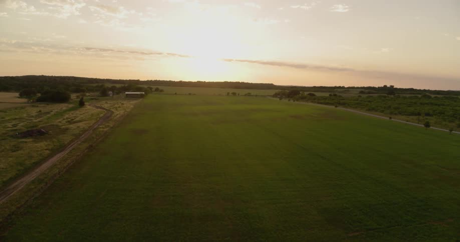 A dirt road runs along side a grass field