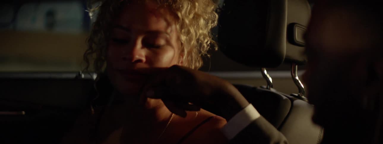 A woman sitting in a car is smiling as a man touches her cheek