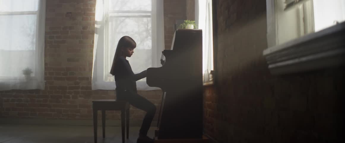 A child is sitting at a piano playing a song