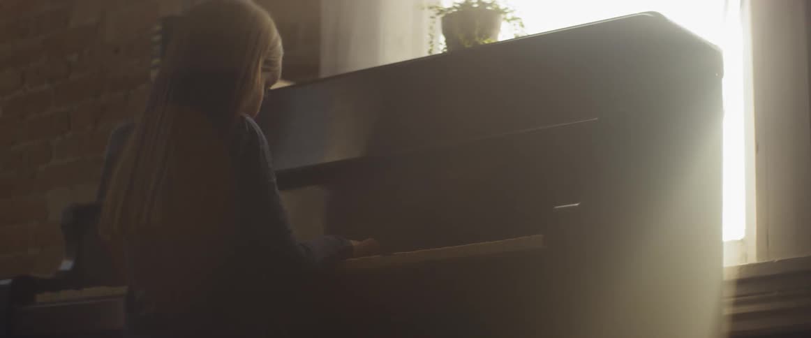 A young girl plays a piano